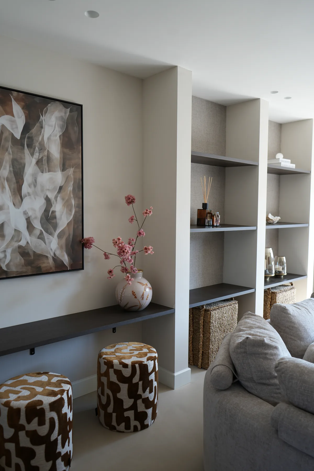 Wandkast met kunst, vaas en poefjes in de woonkamer