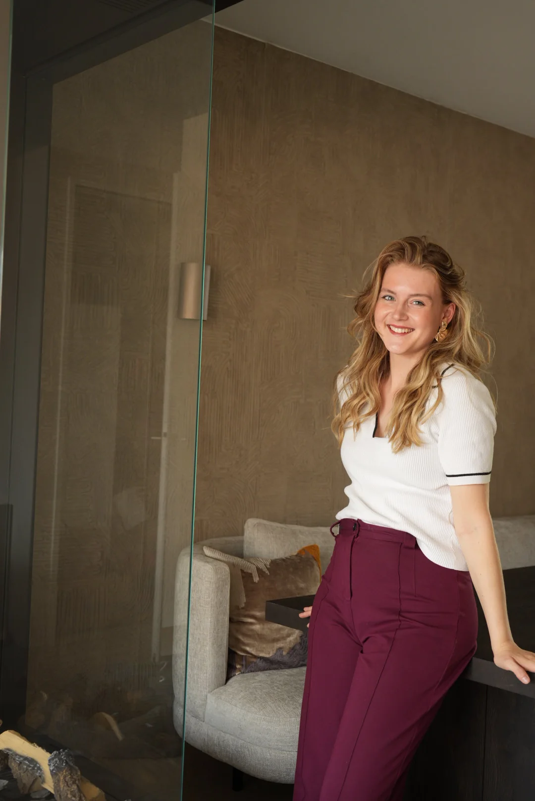 Renée, leunend tegen de eettafel naast de haard