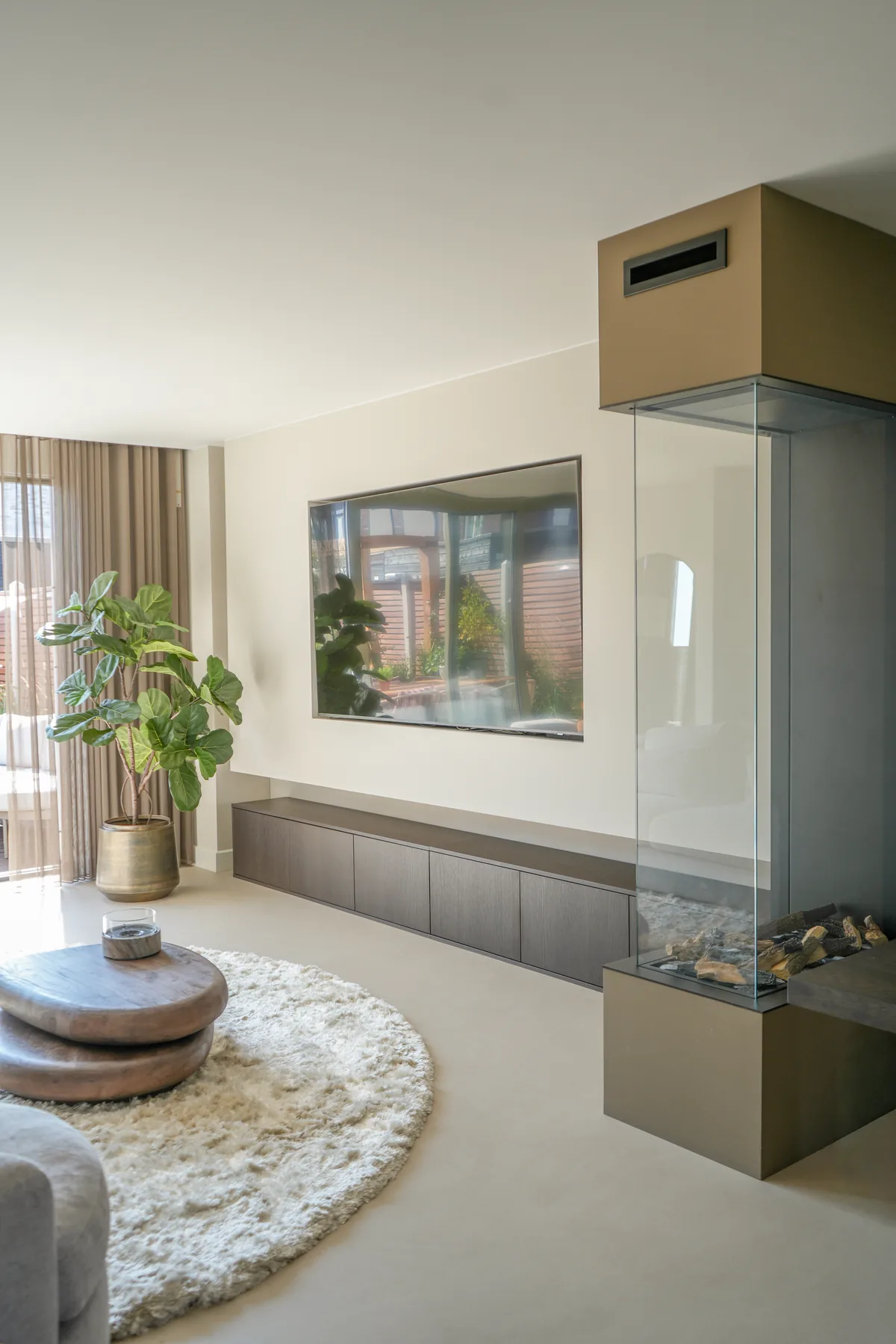 Onze woonkamer met de haard, de cinewall en het ronde kleed